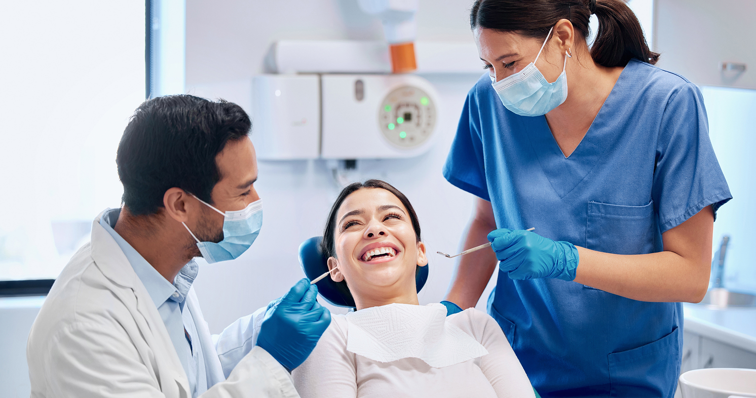Dentist and nurse smiling with patient in dental clinic