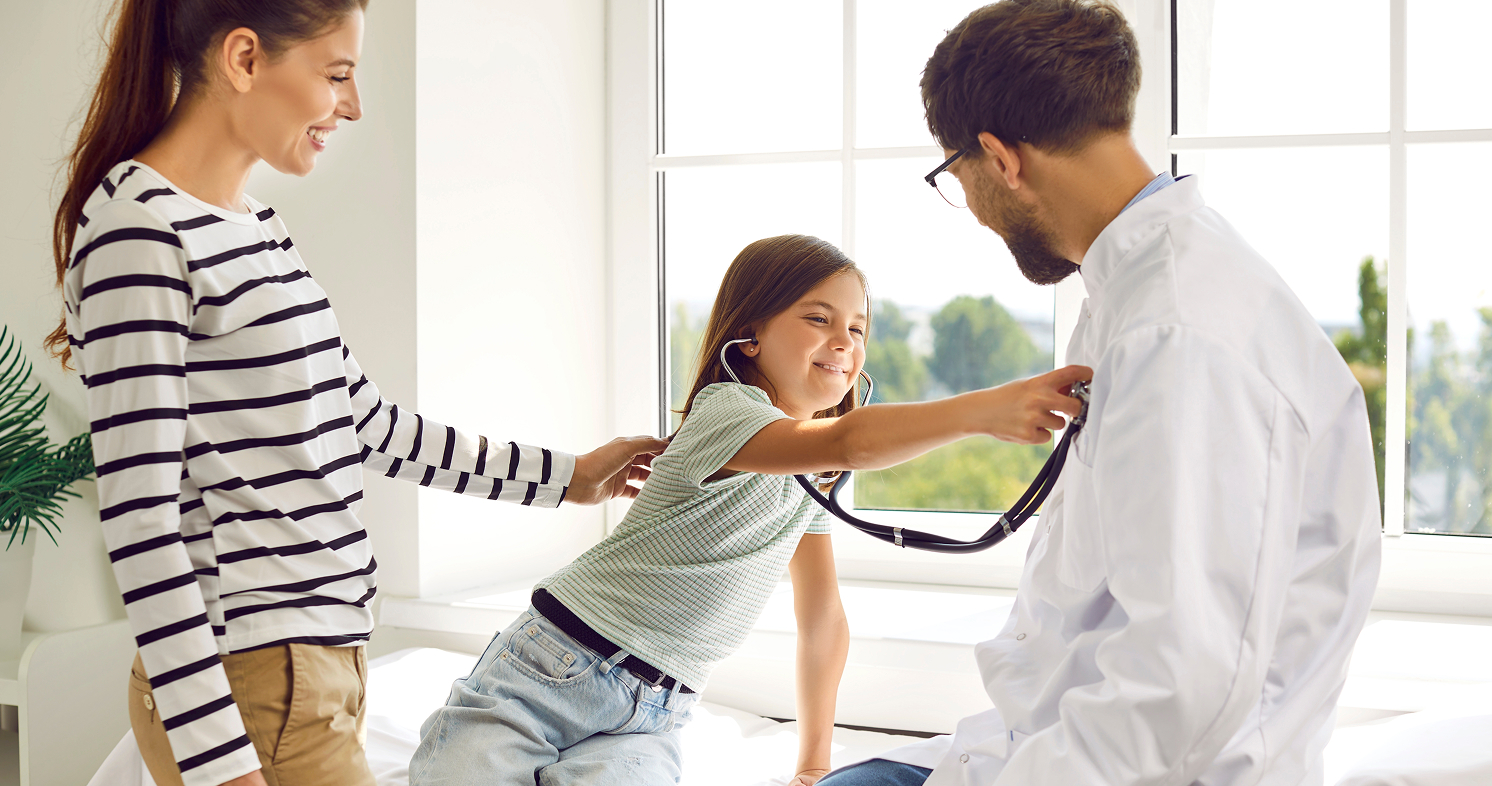 Friendly doctor engaging with mother and child in clinic